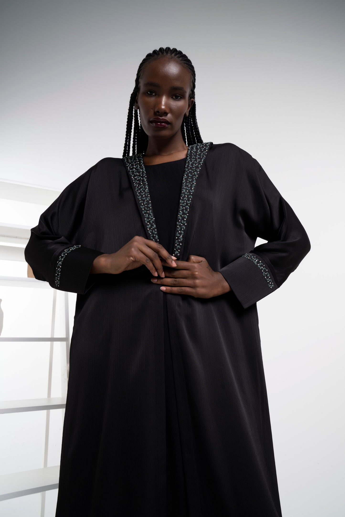 Girl wearing satin abaya with floral embroidery on collar and cuff sleeves