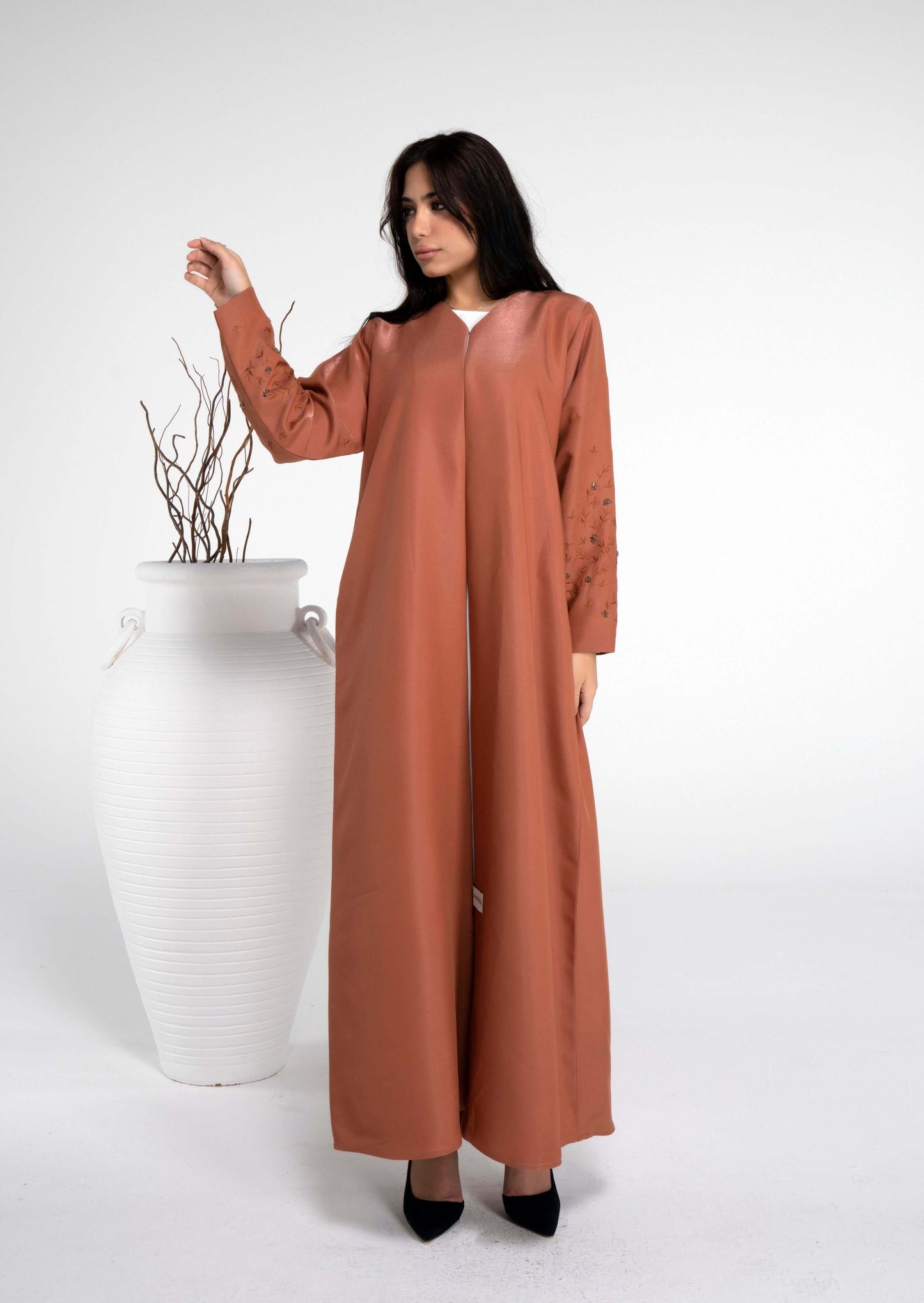 Girl wearing orange abaya with floral embroidered sleeves