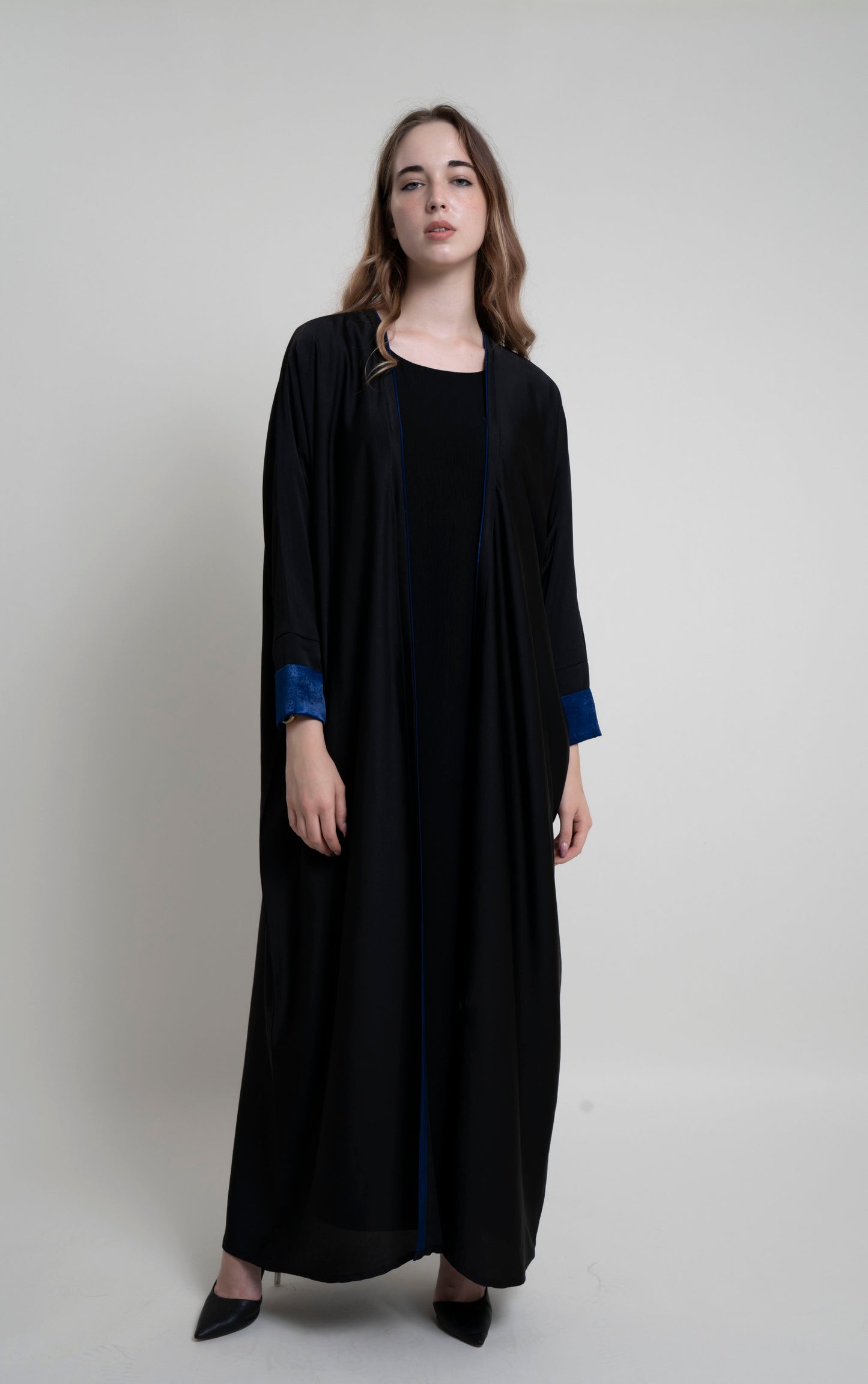 Full view of black bahrini style abaya with blue color cuff sleeve and piping on front line