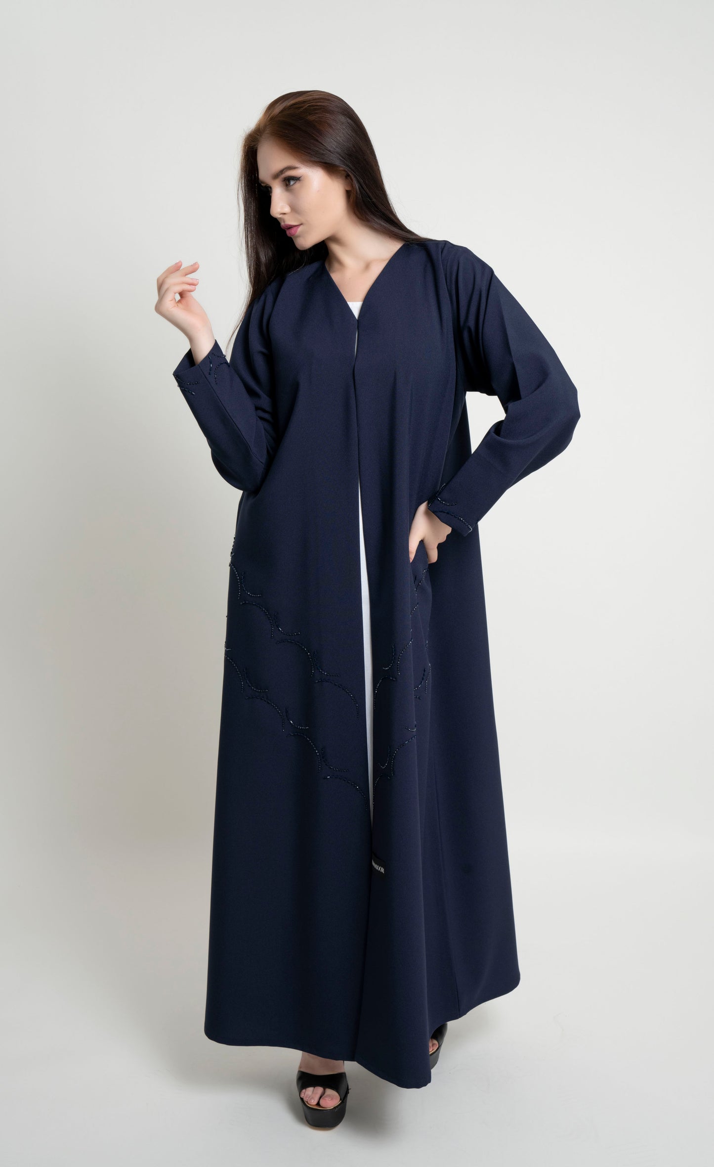 Girl wearing dark blue abaya with curved bead embellishment on front and sleeve