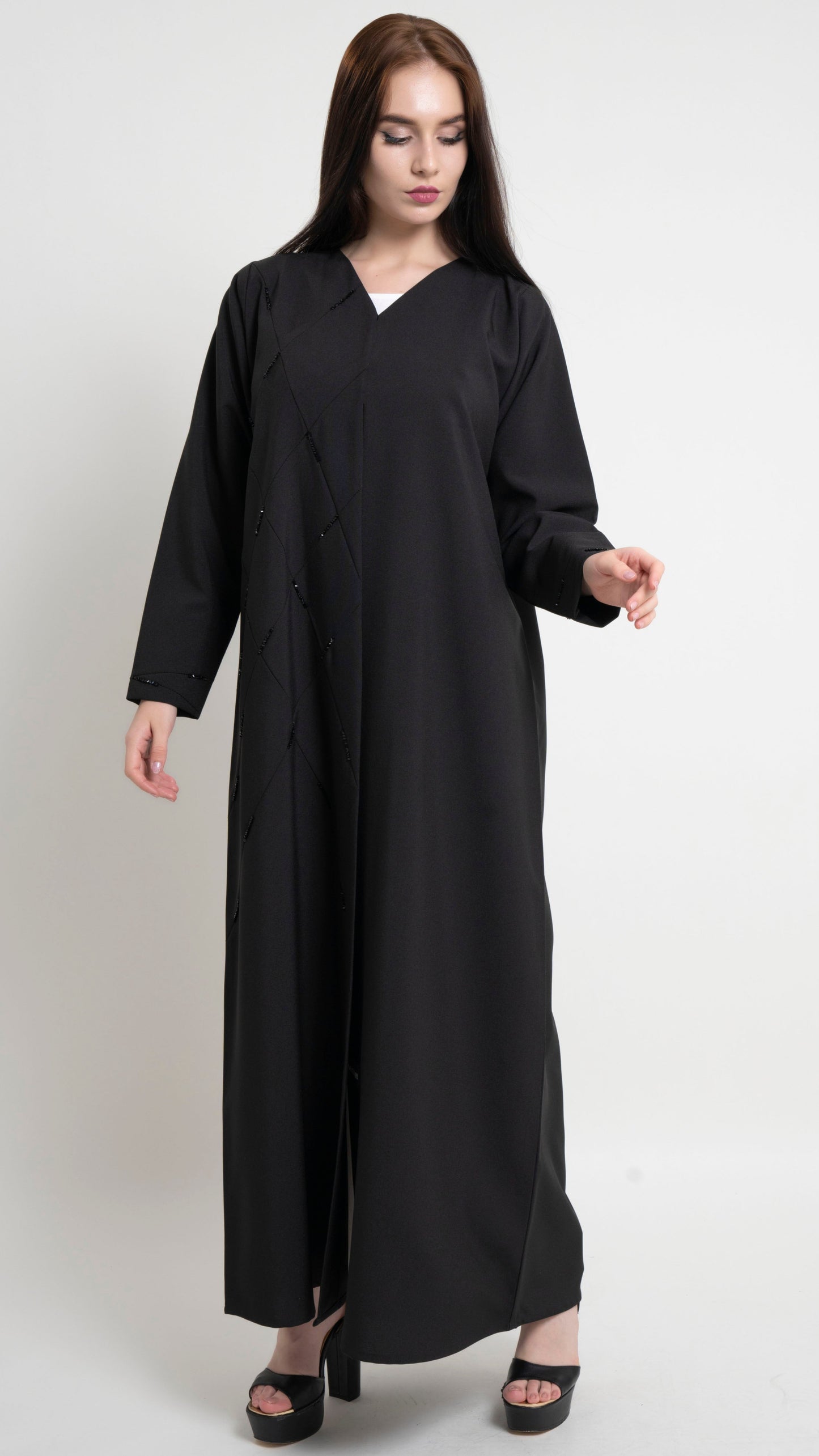 Girl wearing black abaya available in Dubai online with geometric pintucks and embellished with bead detailing