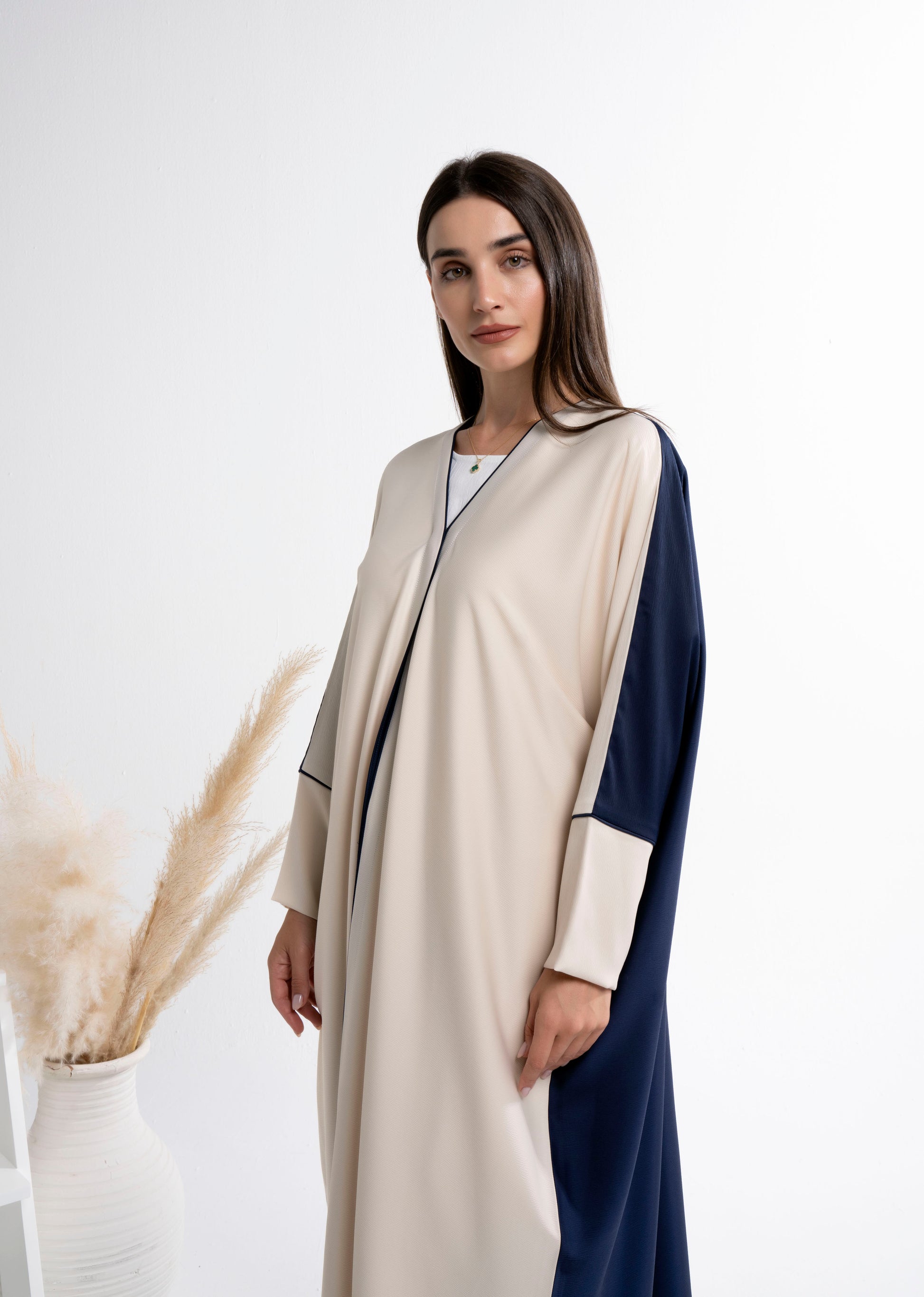 Girl wearing Bahraini style beige & blue color block abaya with front line piping detail.