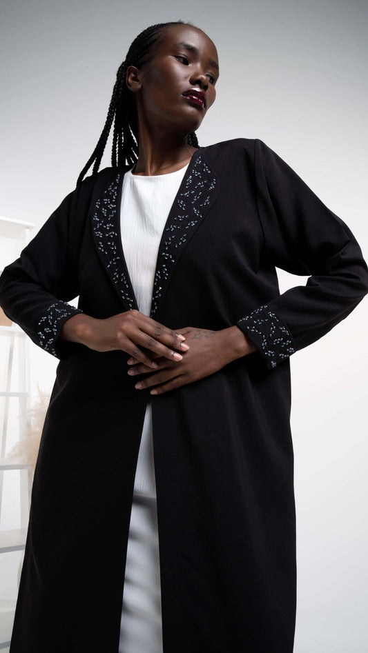 Detailed view of black color abaya with beadwork collar and folded cuff sleeves.