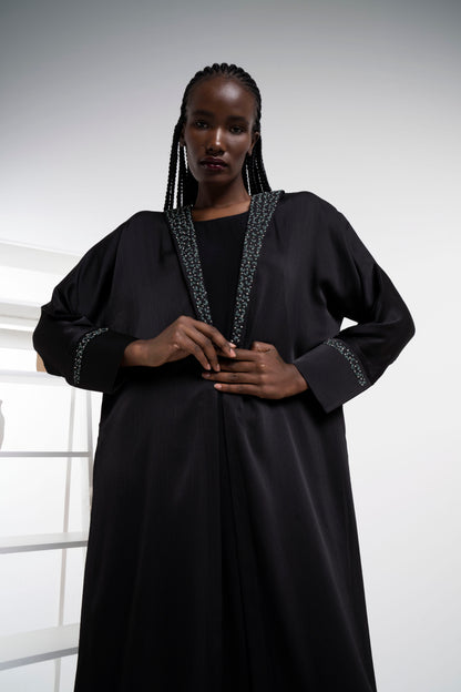 Girl wearing satin abaya with floral embroidery on collar and cuff sleeves