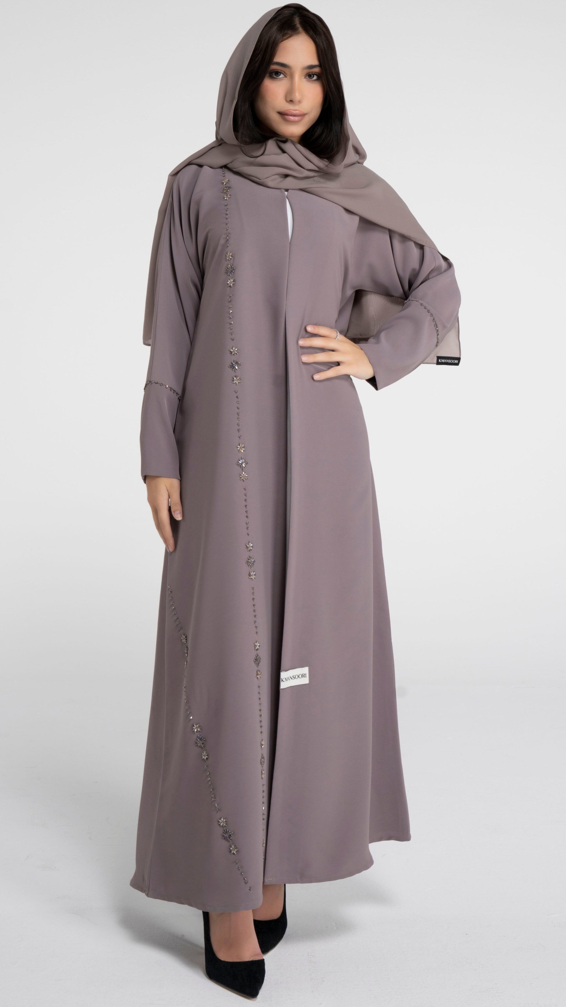 Girl wearing brown abaya with flower motif design line and simple bead line on sleeve. 