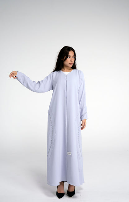 Girl wearing light grey abaya with curve design embellishments