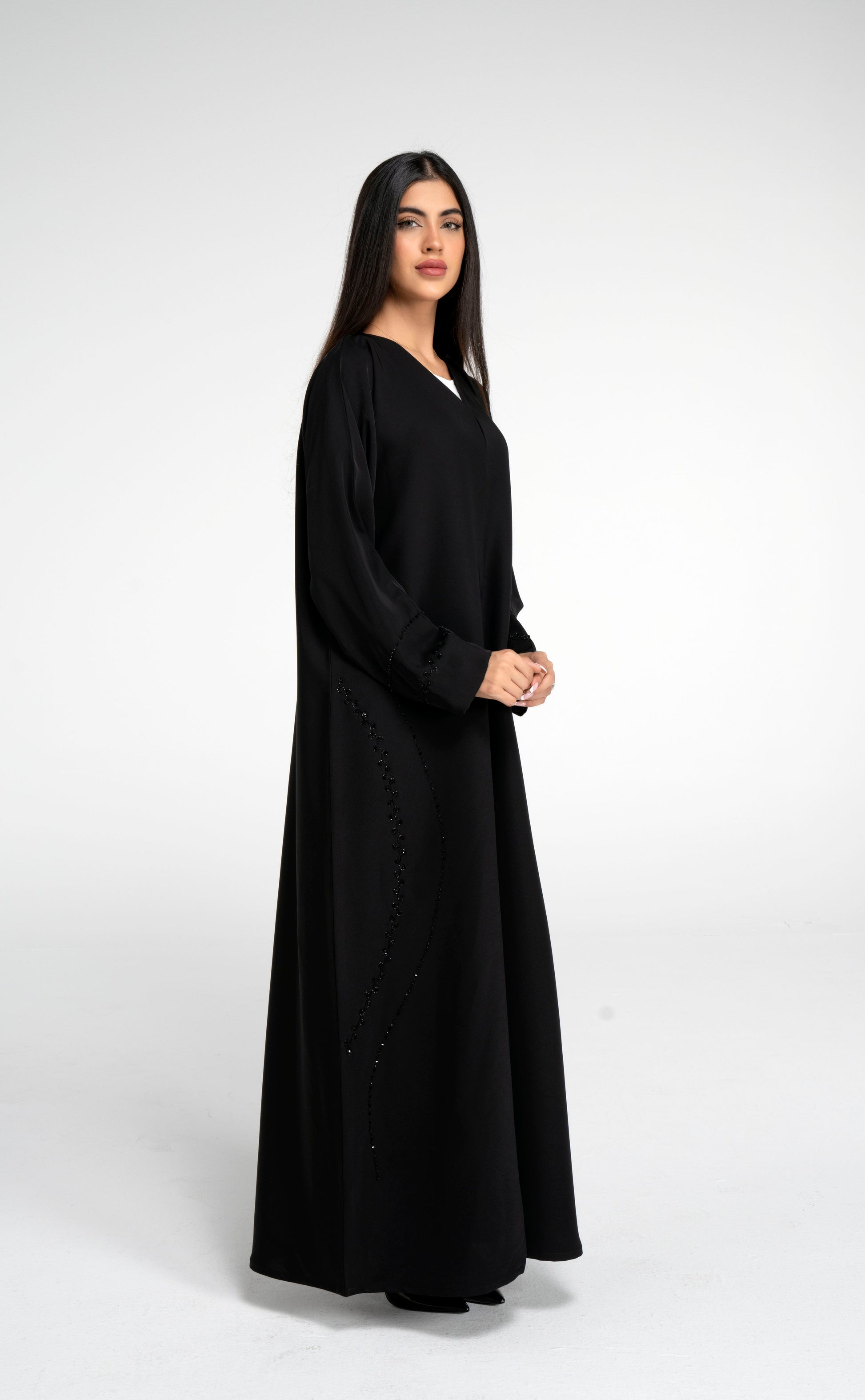 Side view of black abaya with curve design embellishment on front side and sleeve