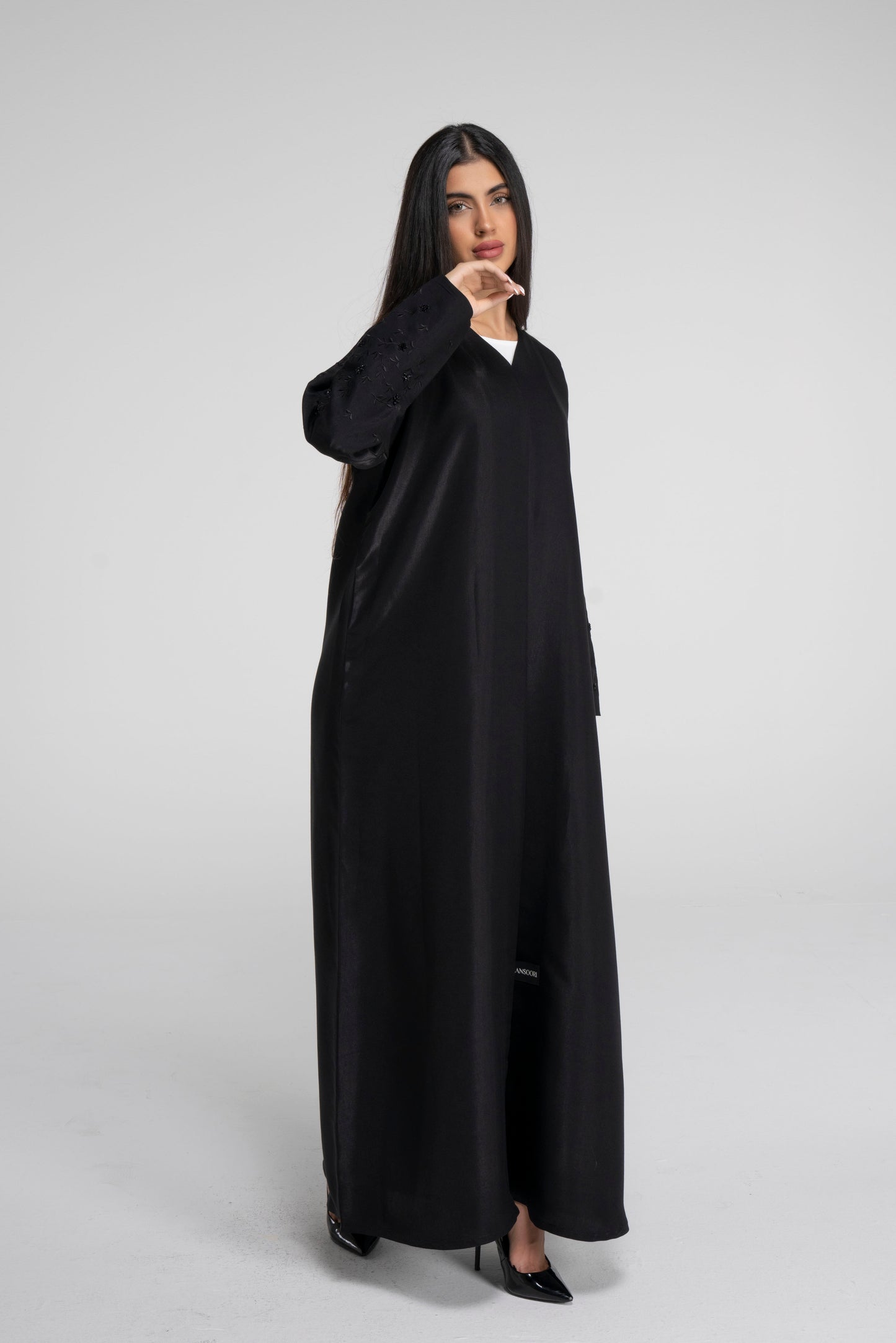 Detailed view of black abaya with floral embroidered sleeves with bead embellishment.