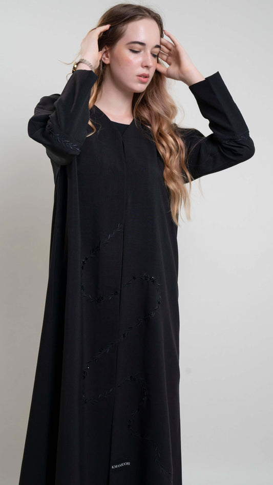 detail view of black abaya with bead embellishments and floral curve line embroidery
