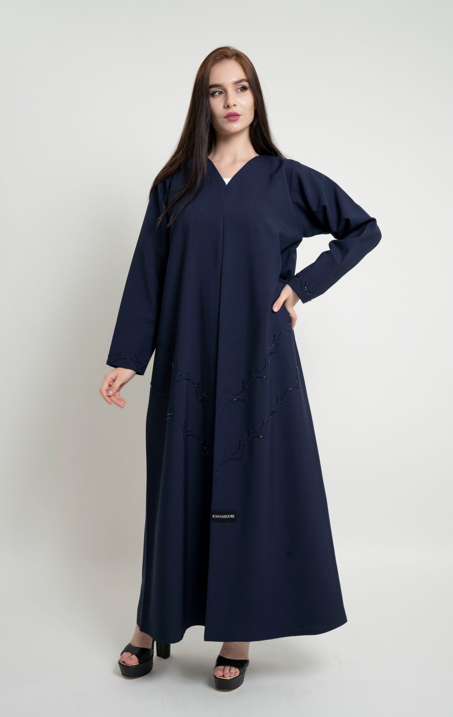 Girl with dark blue abaya with curved bead embellishment on front and sleeve 