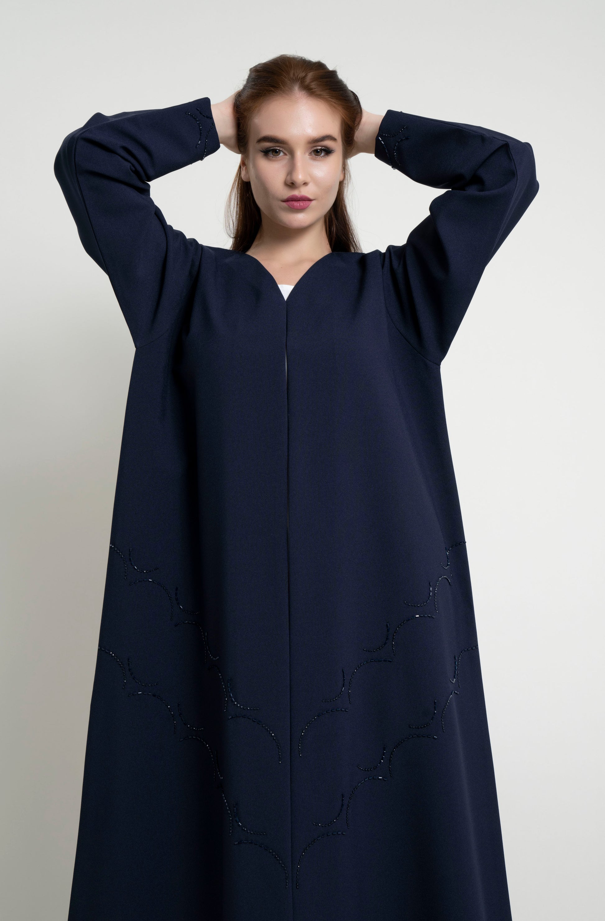 Detailed view of dark blue abaya with curved bead embellishment on front and sleeve 