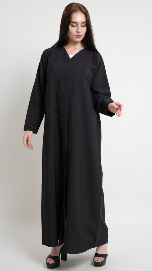 Girl wearing black abaya available in Dubai online with geometric pintucks and embellished with bead detailing
