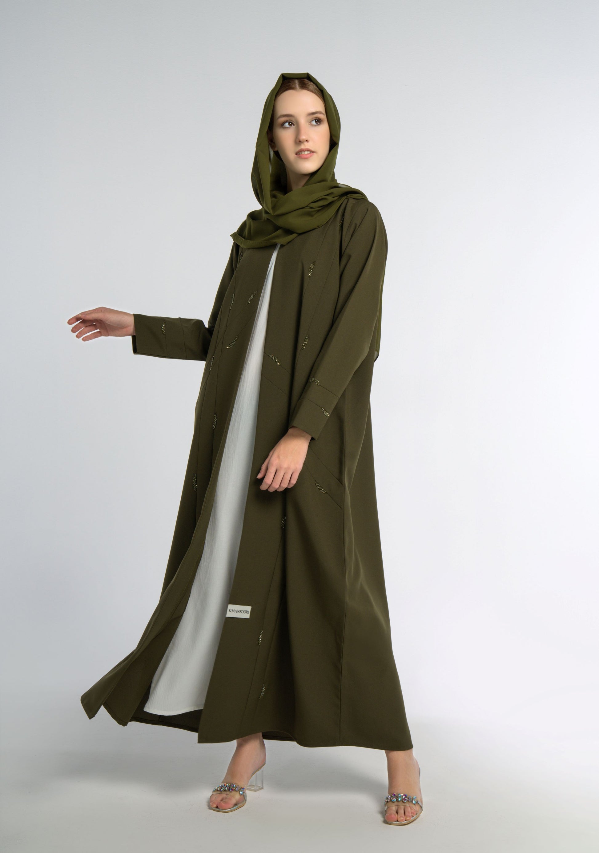 Girl wearing green colored V-neck abaya with elegant line-patterned beaded embellishments.