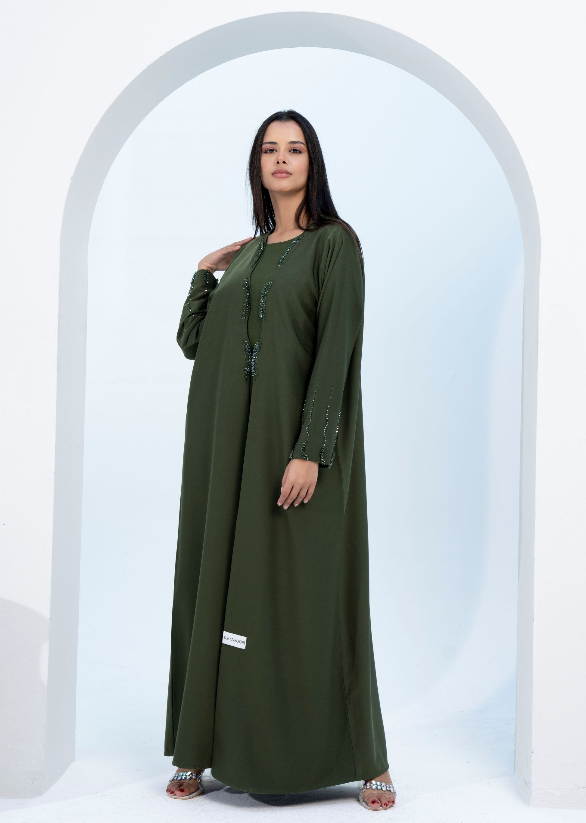 Girl wearing green bisht abaya with curve cut embellishments